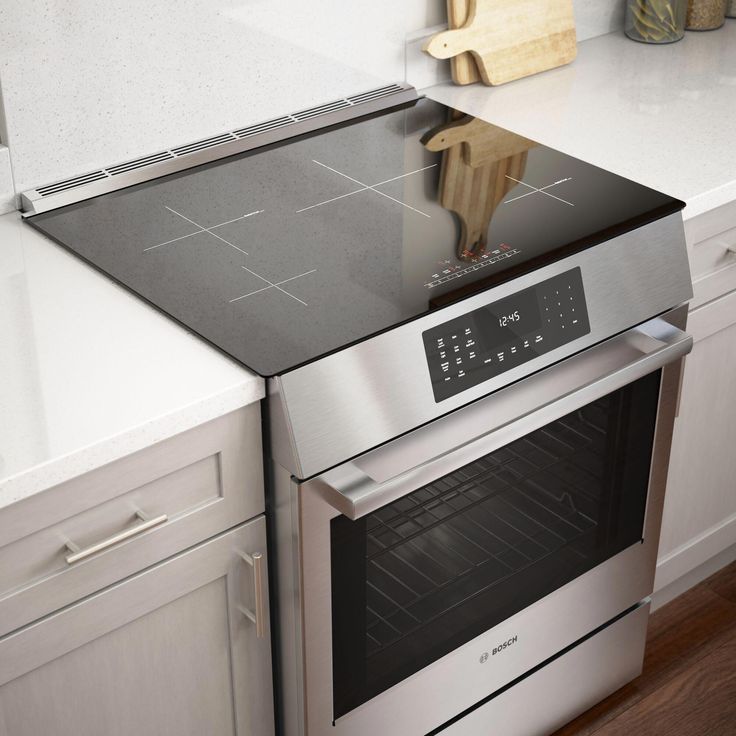 a stainless steel oven with the door open and a wooden cutting board on top of it