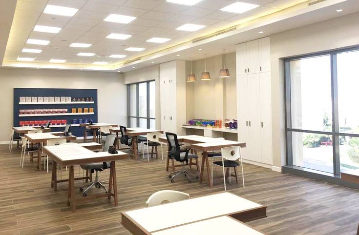 an empty classroom with desks and chairs in front of large windows that look out onto the street