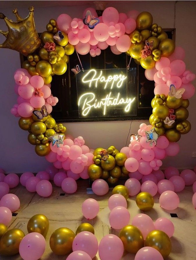 a birthday party with balloons and confetti in the shape of a heart, surrounded by pink and gold balloons