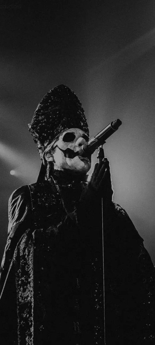 black and white photograph of a man holding a microphone in front of his face while standing on stage