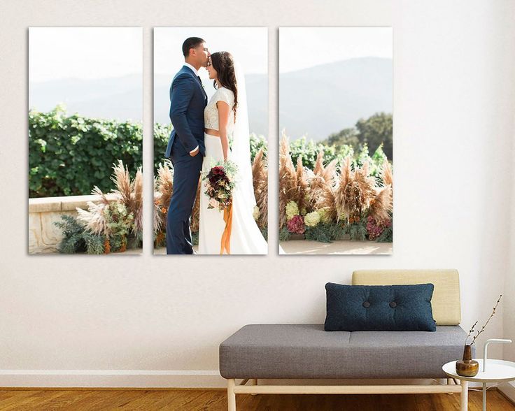 a couple standing next to each other in front of a wall with three pictures on it