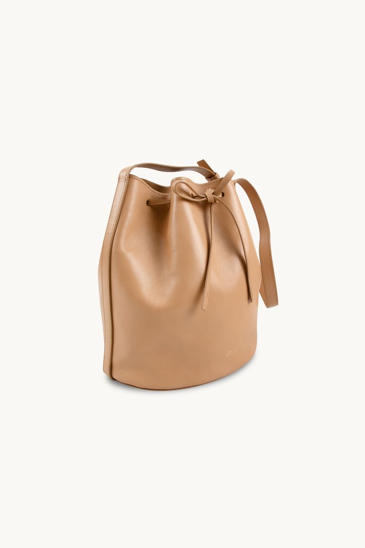 The Anne Leather Bucket Bag in almond is a stylish and versatile accessory that is perfect for any occasion. Crafted from soft 100% leather, this bag is both durable and luxurious. With its spacious interior and adjustable strap, it offers plenty of room for all your essentials while providing comfort and convenience. The almond color adds a touch of elegance to any outfit, making it a must-have accessory now and for many seasons to come.Made in Portugal.The nobility of leather is related to its Almond Color, Tiny Cottons, Leather Bucket, Buckle Sandals, Leather Bucket Bag, Outfit Making, Bucket Bag, Adjustable Straps, Portugal