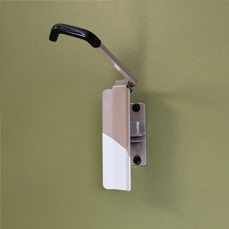 a wall mounted light fixture on the side of a green wall with a black handle