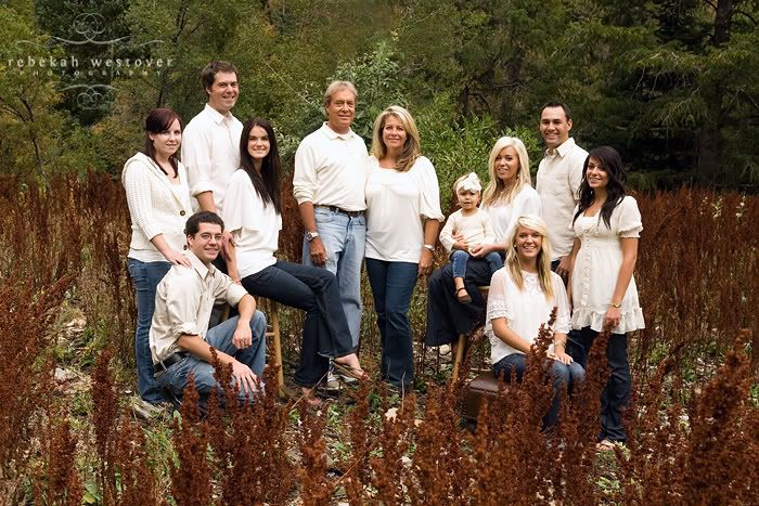 a group of people posing for a photo in front of some tall grass and trees