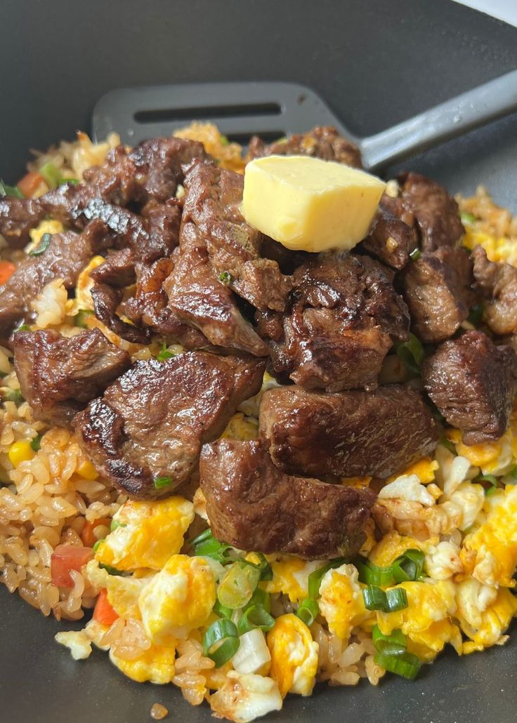 meat and rice in a skillet with a buttered piece of butter on top