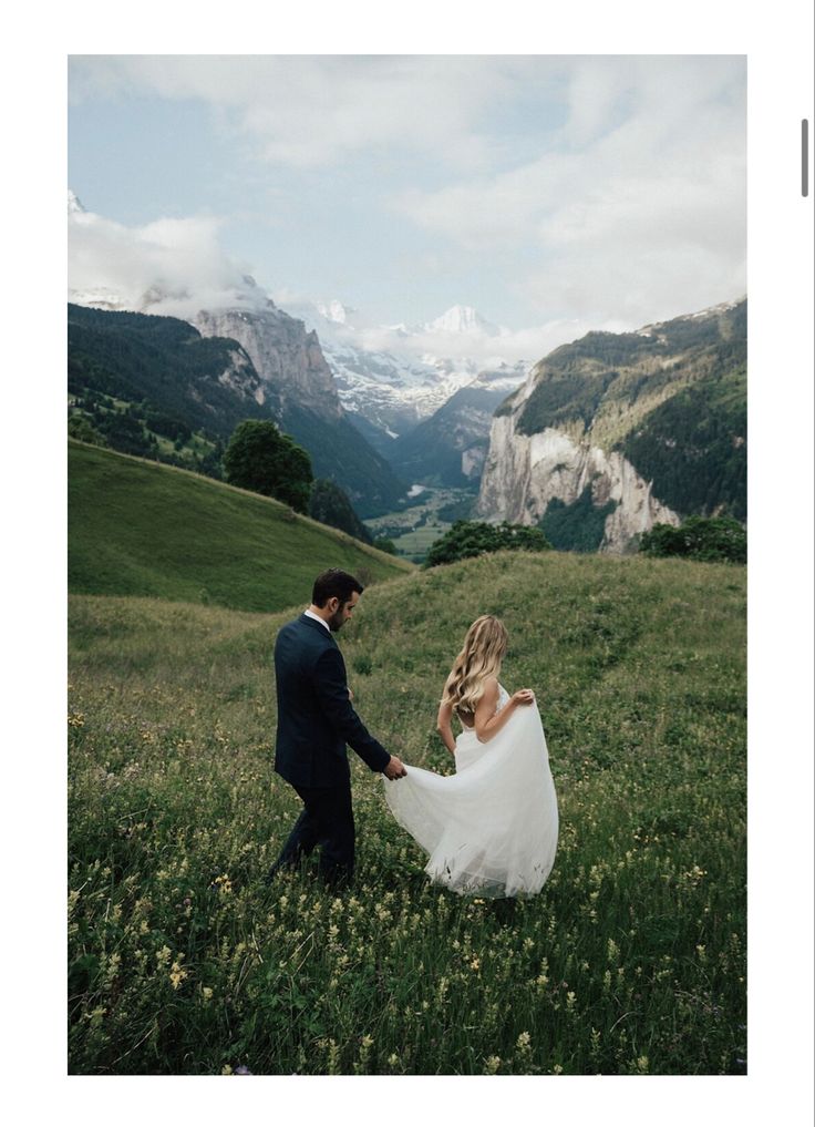 a bride and groom holding hands in the mountains