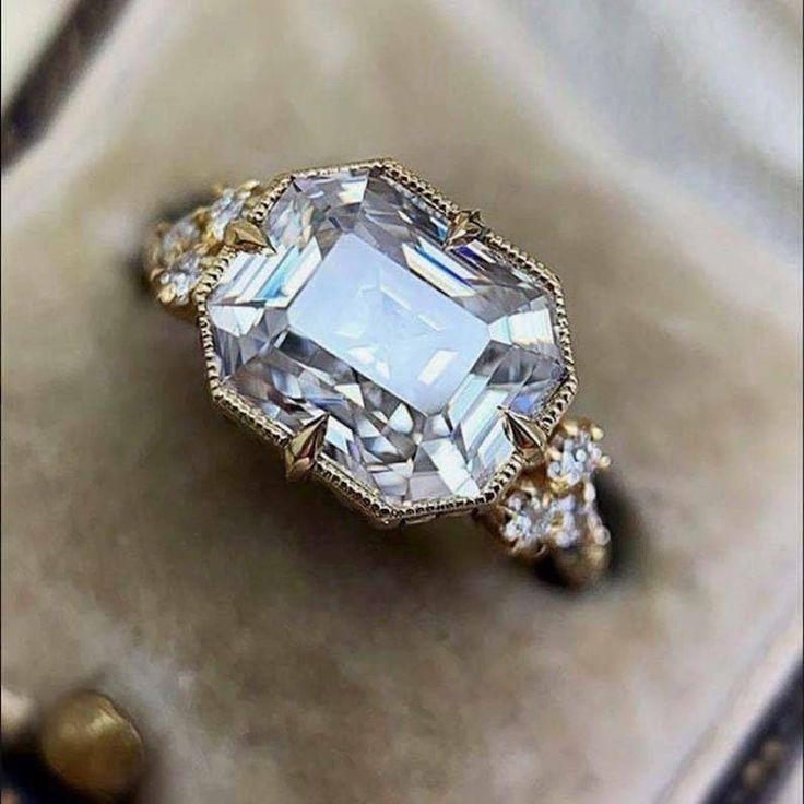 an engagement ring with a large white diamond surrounded by smaller diamonds on top of it