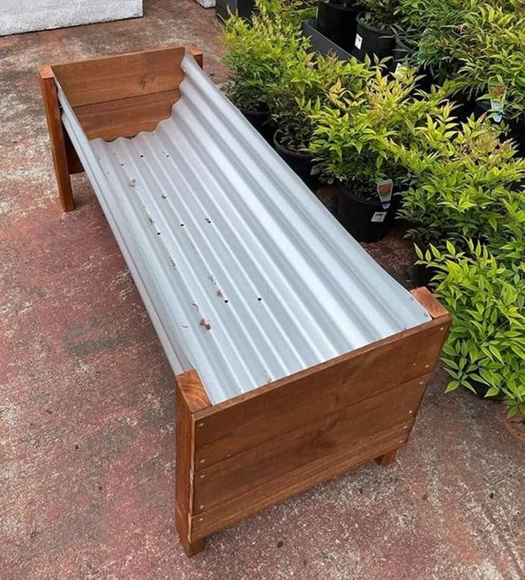 a wooden bench with metal slats on top of it next to potted plants