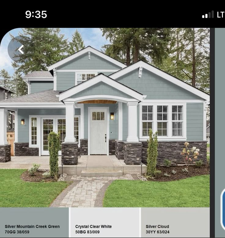 a blue house with white trim on the front and side doors, windows, and landscaping