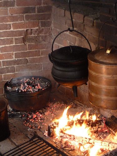 an open fire pit with pots and pans on the stove top next to it