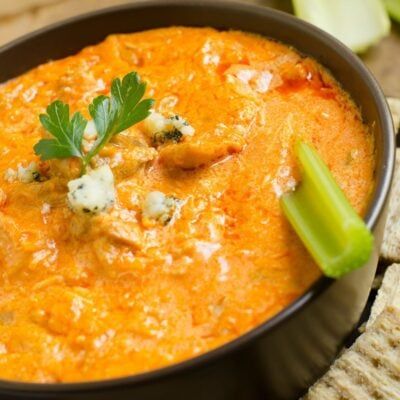 a close up of a bowl of food with celery and cheese on top