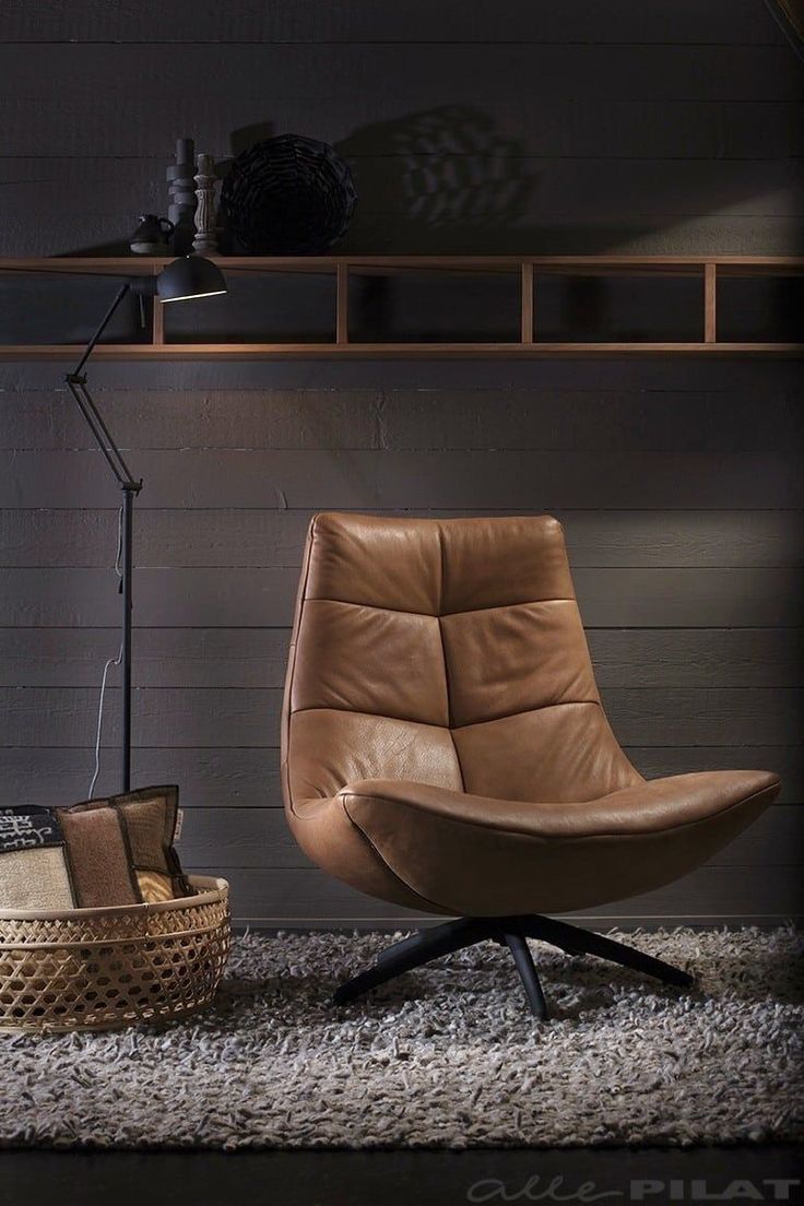 a brown leather chair sitting on top of a rug next to a lamp and basket