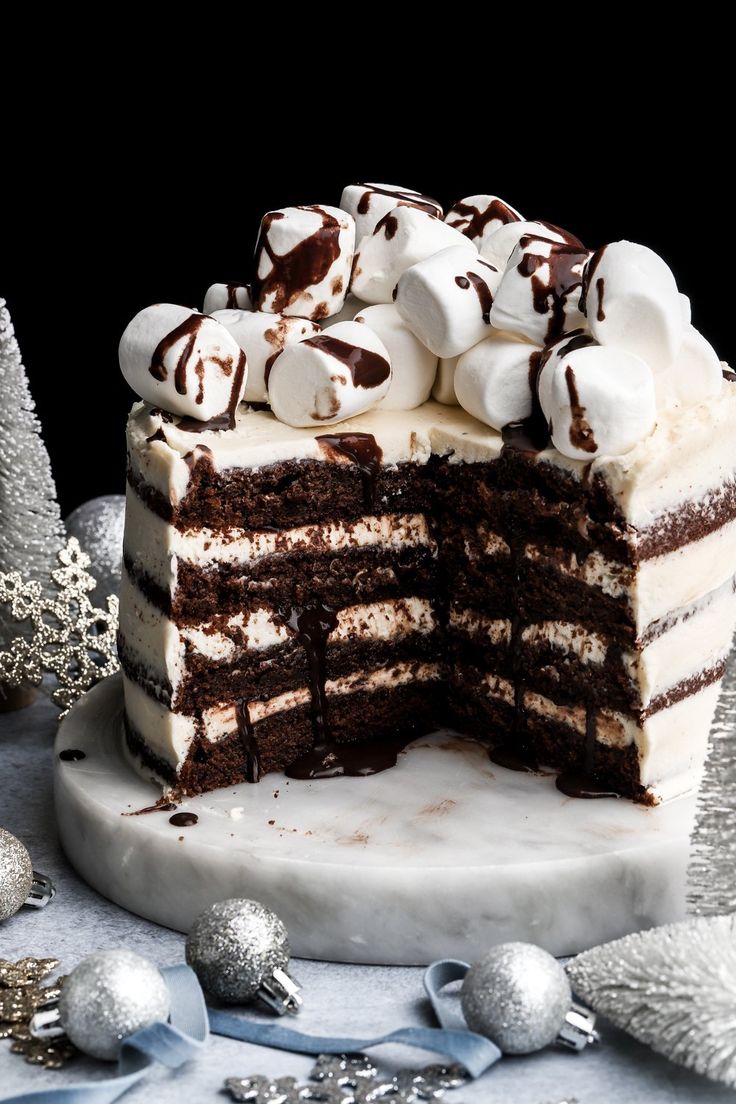 a large slice of cake with marshmallows on top is shown in front of silver ornaments