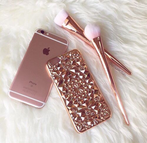 an iphone and makeup brush are laying on a white furnishing next to each other