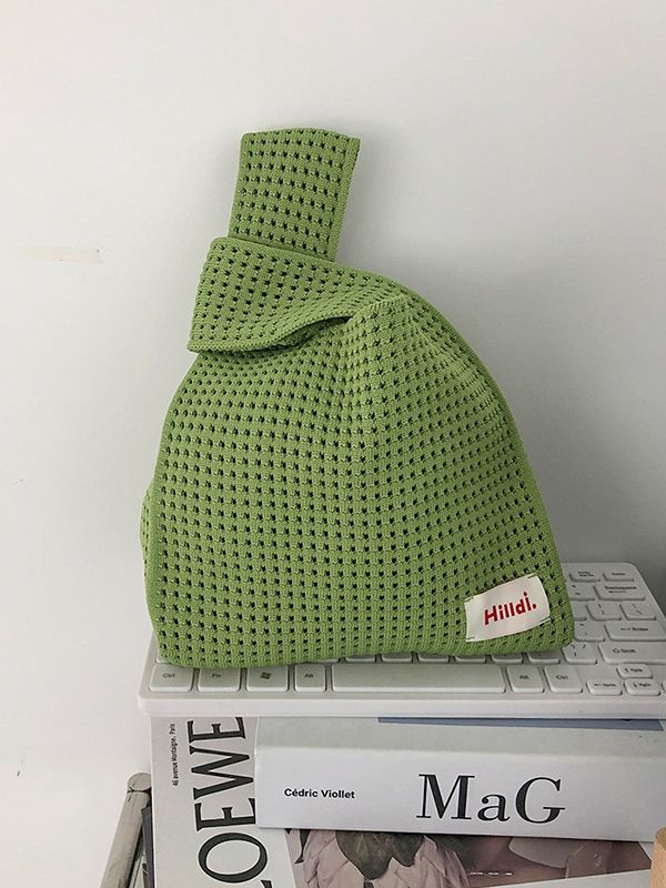 a green knitted bag sitting on top of some books