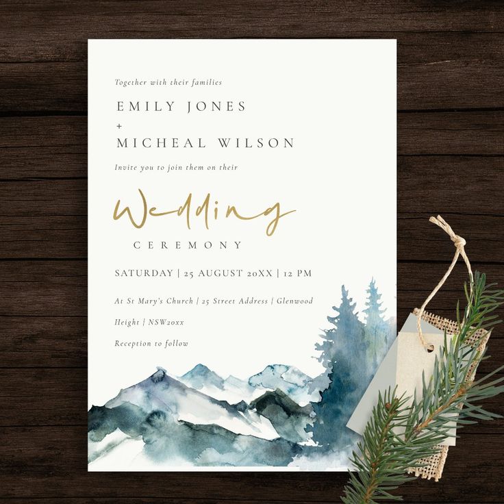 a wedding card with watercolor mountains and pine trees on it, next to a plant