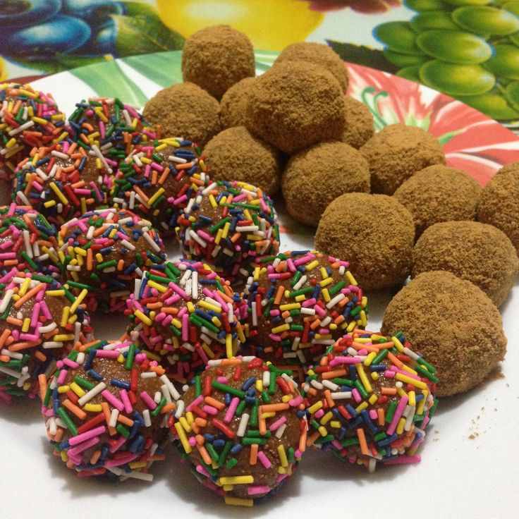 several chocolate donuts with sprinkles are on a plate next to other treats