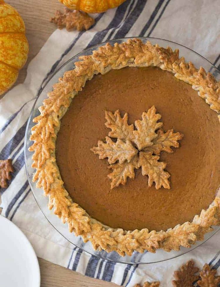 there is a pie with frosting on it and some leaves next to the pie