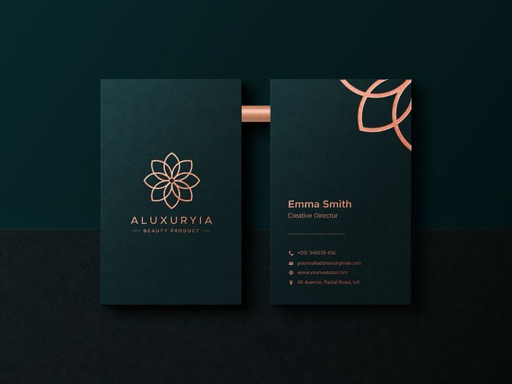 two black business cards with gold foil on the front and back, against a dark green background