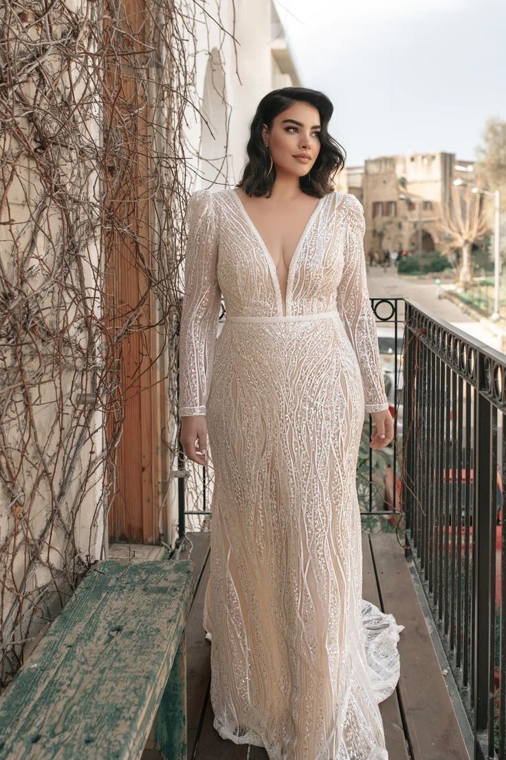 a woman in a white dress standing on a balcony next to a fence and looking off into the distance