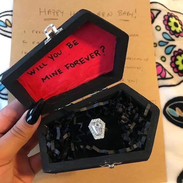 someone is holding an open ring box with the message will you be mine forever?