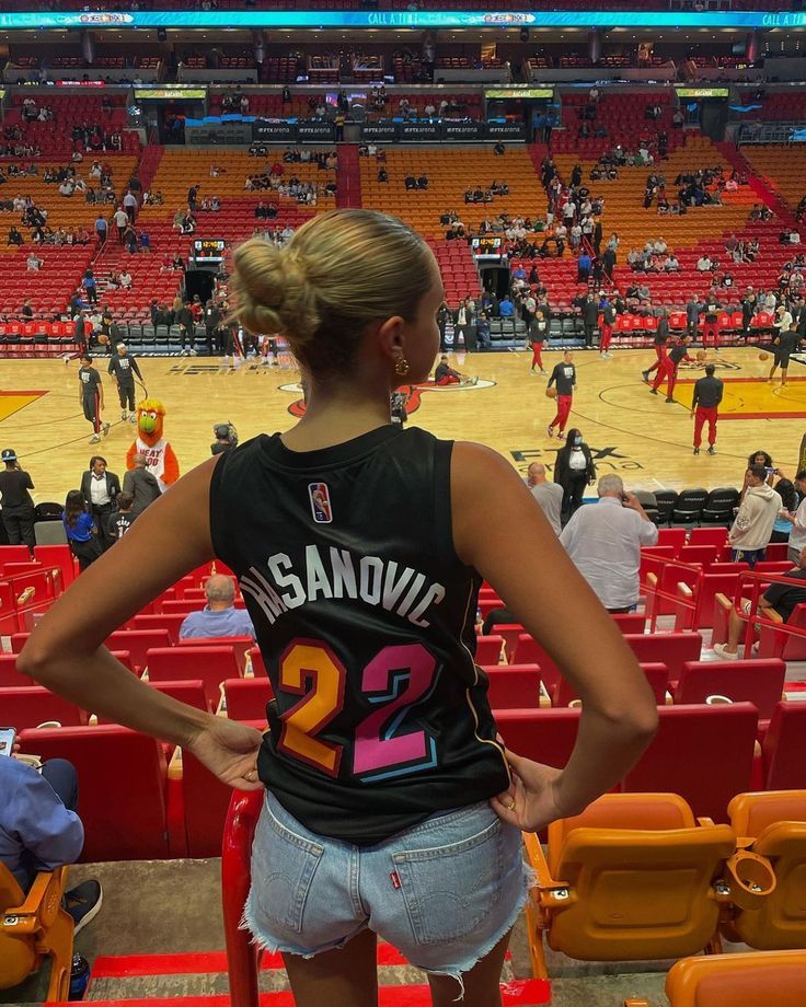 a woman standing in front of a basketball court with her back turned to the camera