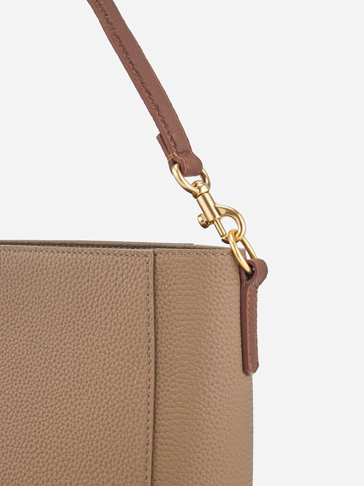 The Carrie Bucket Bag is a stylish and functional staple piece made of full-grain Italian pebbled leather. It features a spacious interior with a zipper closure, a top handle, an adjustable webbing strap, and luxurious leathered lining. Its classic silhouette, gold-plated hardware, and essential color options make it a versatile accessory that can elevate any outfit, perfect for the modern woman on-the-go. Modern Leather Baguette Bag With Leather Handles, Everyday Satchel With Handle Drop In Pebbled Leather, Modern Bucket Bag With Gold-tone Hardware For Everyday Use, Beige Pebbled Leather Bag With Gold-tone Hardware, Textured Leather Double Handle Bag, Double Handle Textured Pebbled Leather Bag, Beige Pebbled Leather Shoulder Bag With Double Handle, Beige Pebbled Leather Satchel With Double Handle, Pebbled Leather Bucket Bag With Detachable Strap