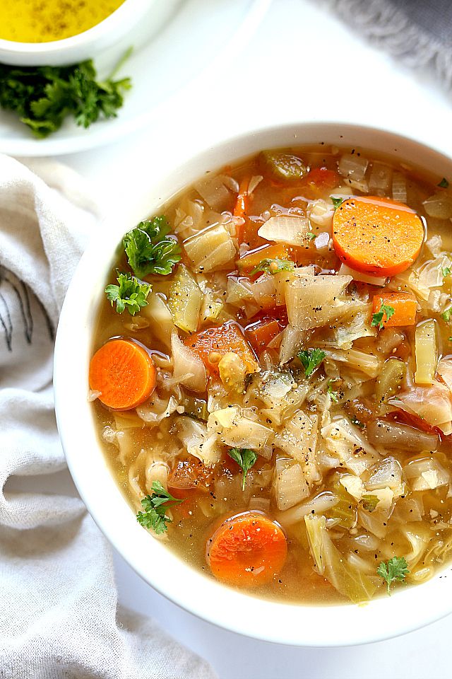 a bowl of soup with carrots, onions and parsley