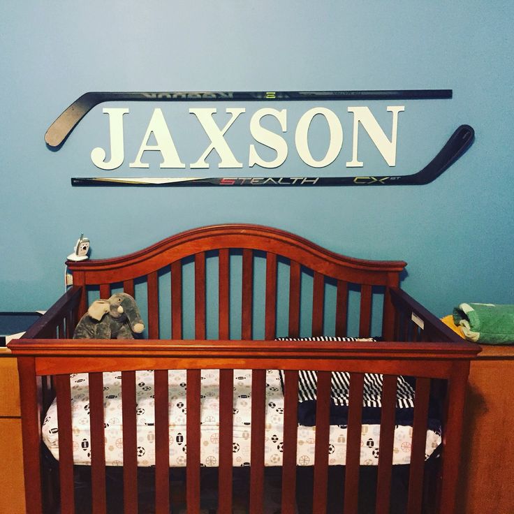 a baby crib in front of a blue wall with a name sign above it