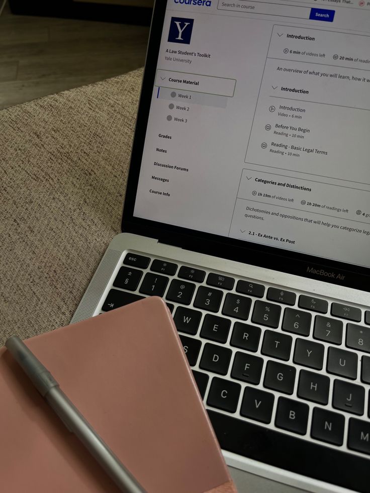 an open laptop computer sitting on top of a desk next to a notepad and pen