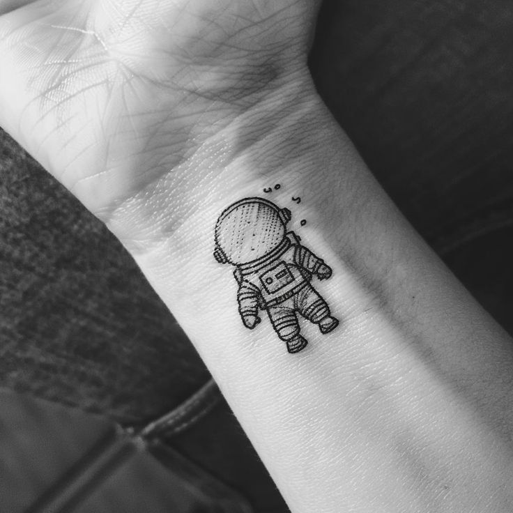 a small tattoo on the wrist of a person with an astronaut's suit on it