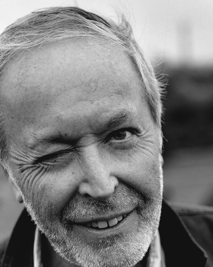 black and white photograph of an older man smiling at the camera with his eyes closed