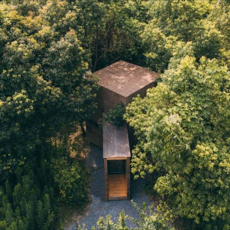 an aerial view of a wooden structure in the middle of some trees and bushes, surrounded by greenery