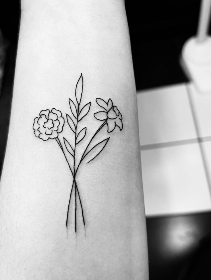 a black and white photo of a flower tattoo on the left inner arm, which has three flowers in it