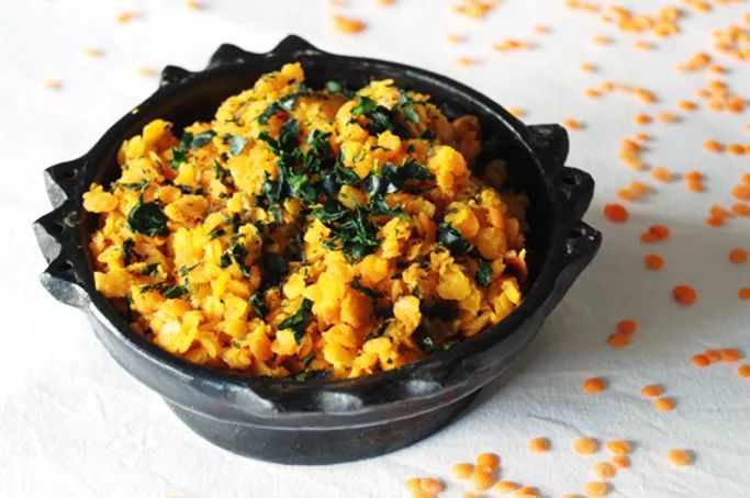 a black bowl filled with food sitting on top of a white table covered in orange dots