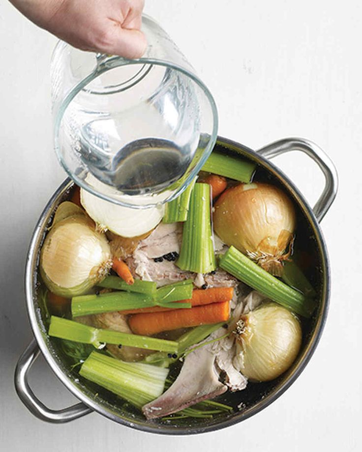 someone pouring water into a pot filled with vegetables