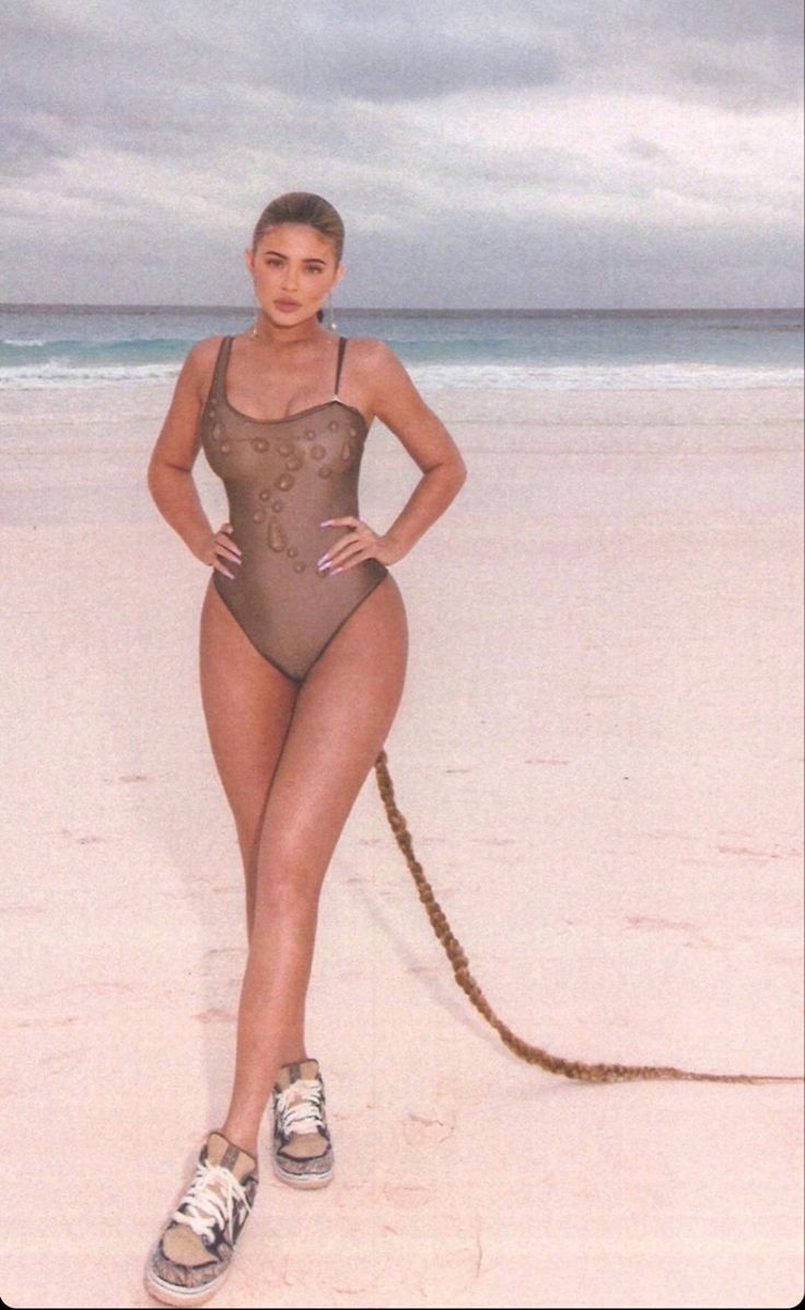 a woman in a bodysuit standing on the beach