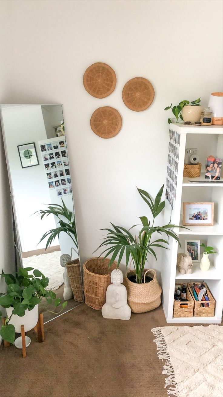 a living room filled with lots of plants next to a tall white book shelf covered in pictures