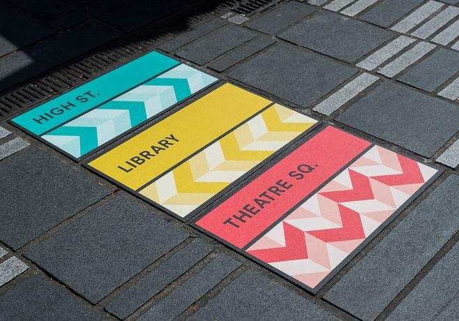 there are three signs on the sidewalk that say library, theatre, and high school