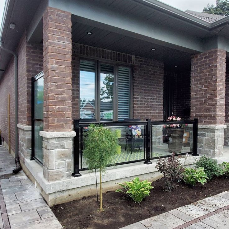 a brick house with glass balconies on the front porch and side yard area