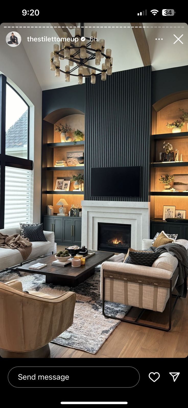 a living room filled with furniture and a fire place under a chandelier in front of a large window