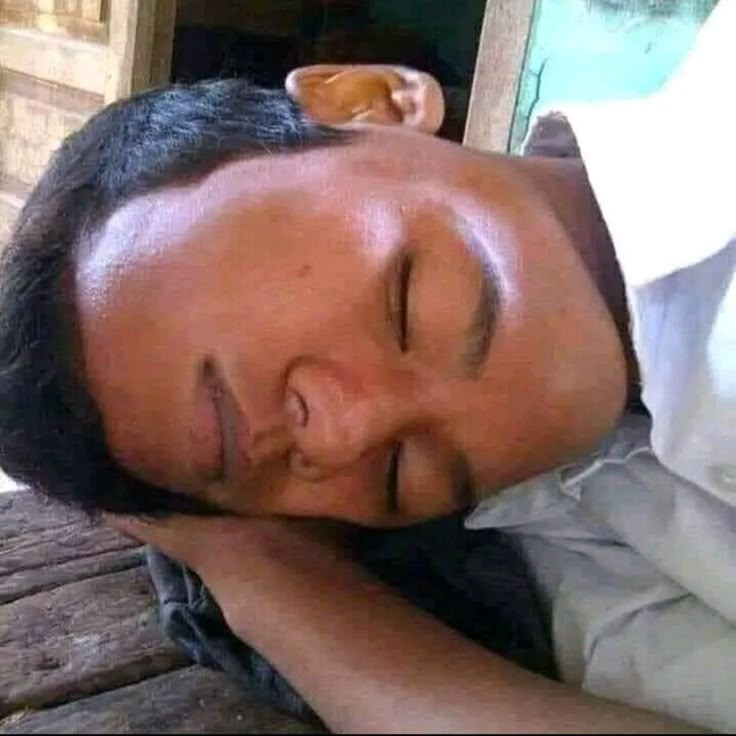 a man sleeping on top of a wooden table