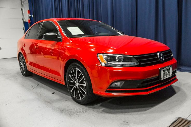 a red car is parked in front of a blue curtain and some black rims