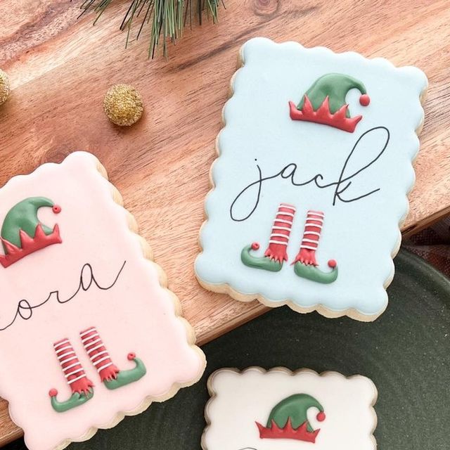 three decorated cookies sitting on top of a wooden cutting board next to christmas tree decorations