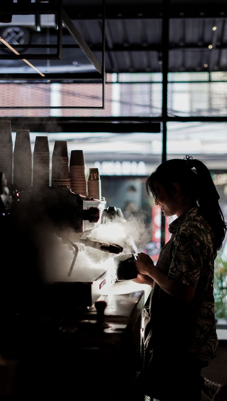 a woman standing in front of a stove cooking food on top of a counter next to a window