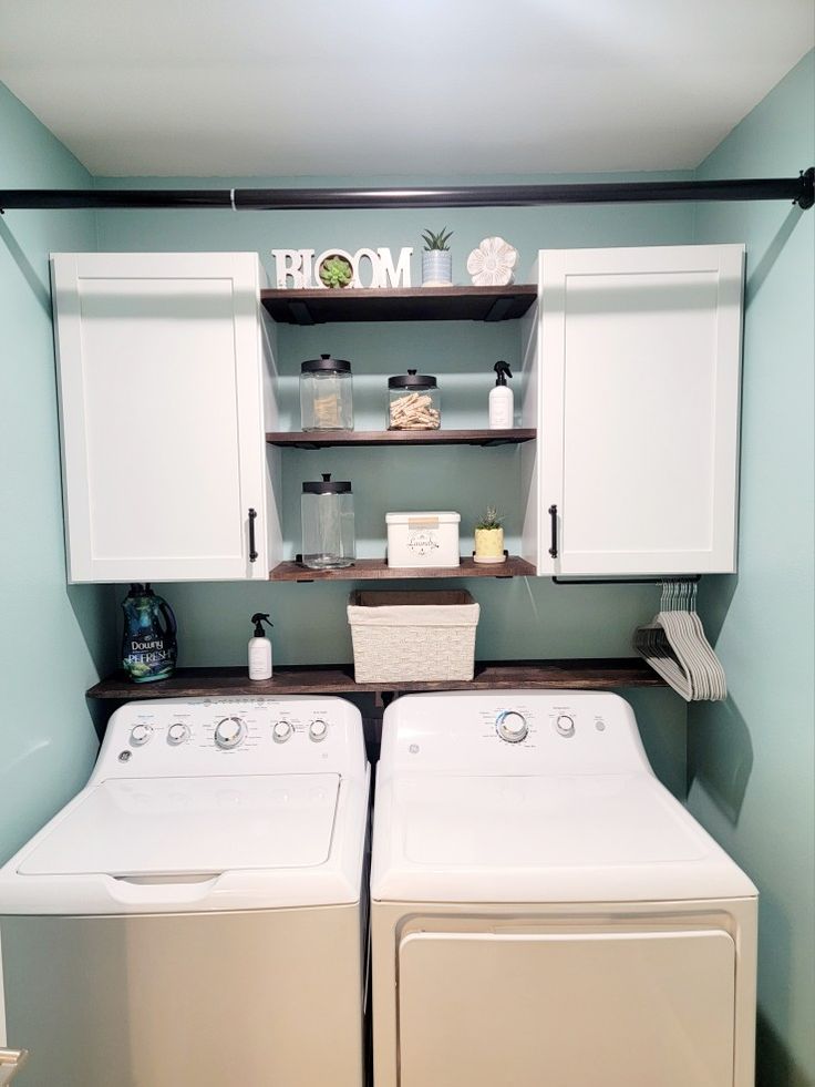 a washer and dryer in a laundry room with cabinets above them that are open