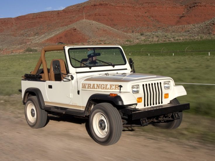 a white jeep driving down a dirt road