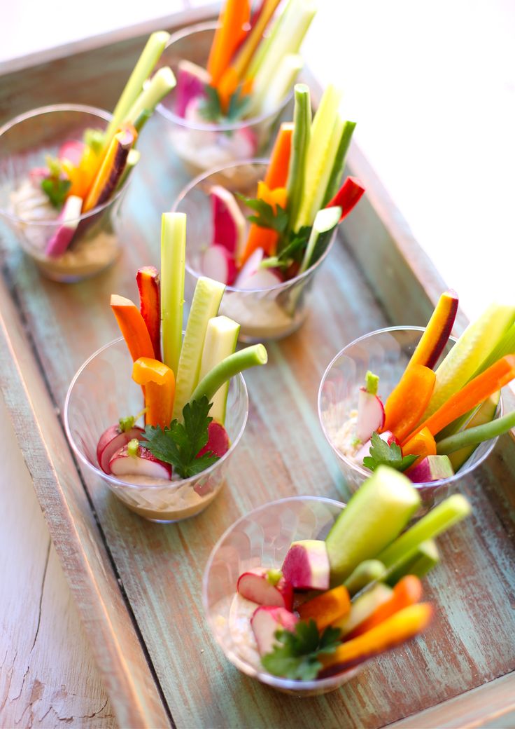 several small bowls filled with different types of veggies on top of a wooden tray