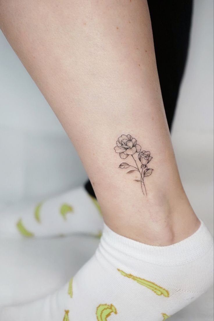 a woman's foot with a small flower tattoo on her left side calfocks