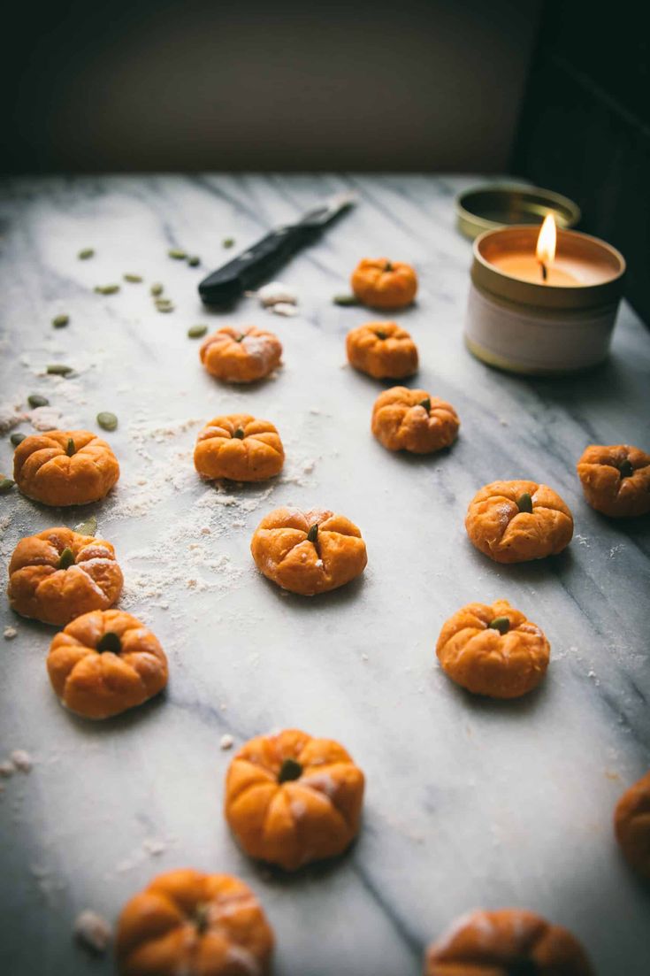 small pumpkins are arranged on a baking sheet with a candle in the middle and scattered seeds around them